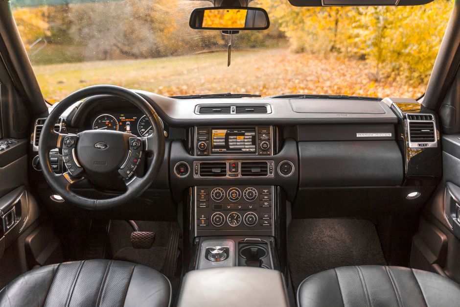 Elegant Range Rover interior showcasing modern design and leather seats, captured in autumn light.